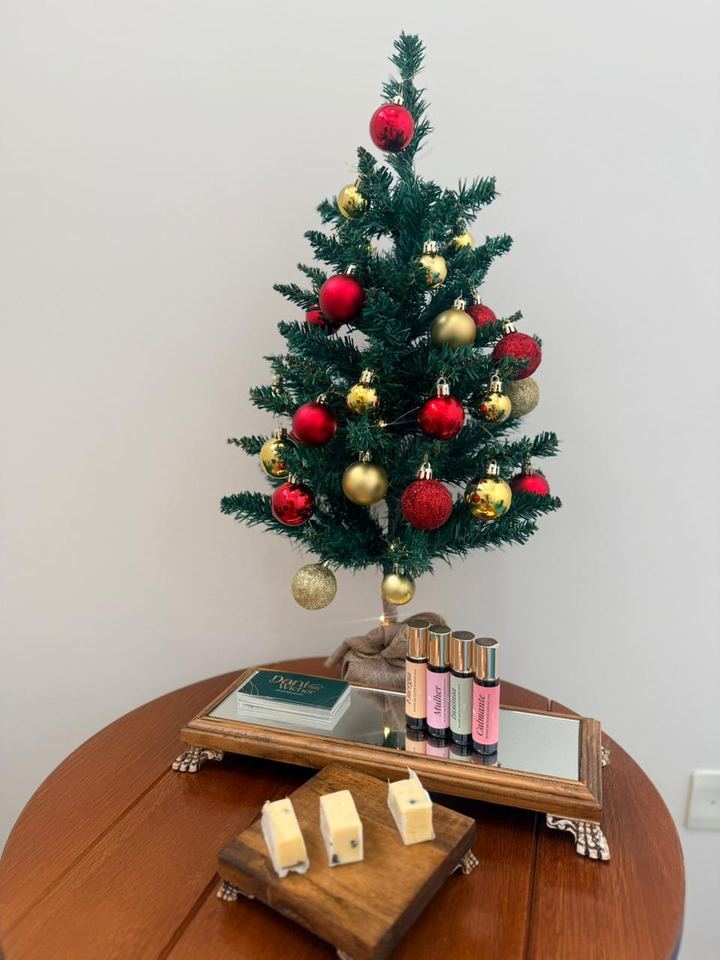 Árvore de Natal decorada sobre a mesa, com frascos aromáticos ao lado