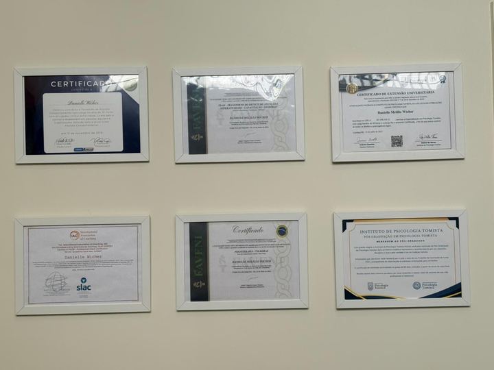 Parede do consultório com seis certificados emoldurados