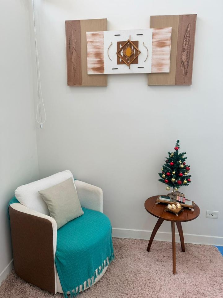 Poltrona com manta verde, quadros na parede e pequena árvore de Natal