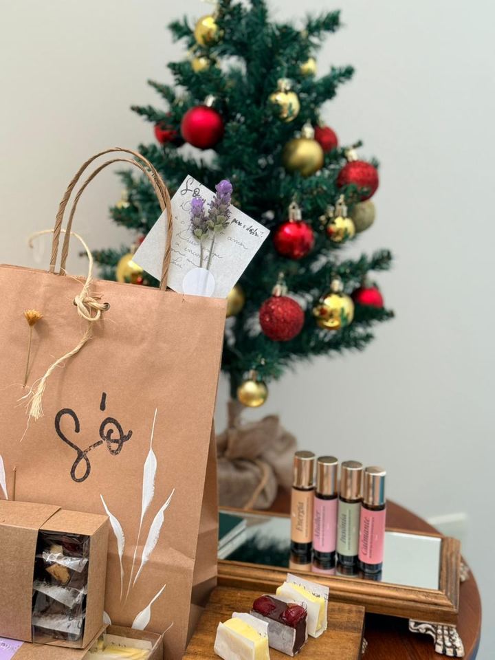 Sacola de papel kraft e caixas de doces ao lado de uma árvore de Natal